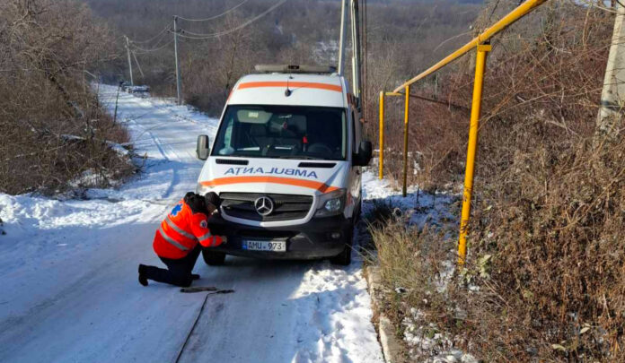Salvatorii tractează o ambulanță blocată pe un drum acoperit cu ghețuș